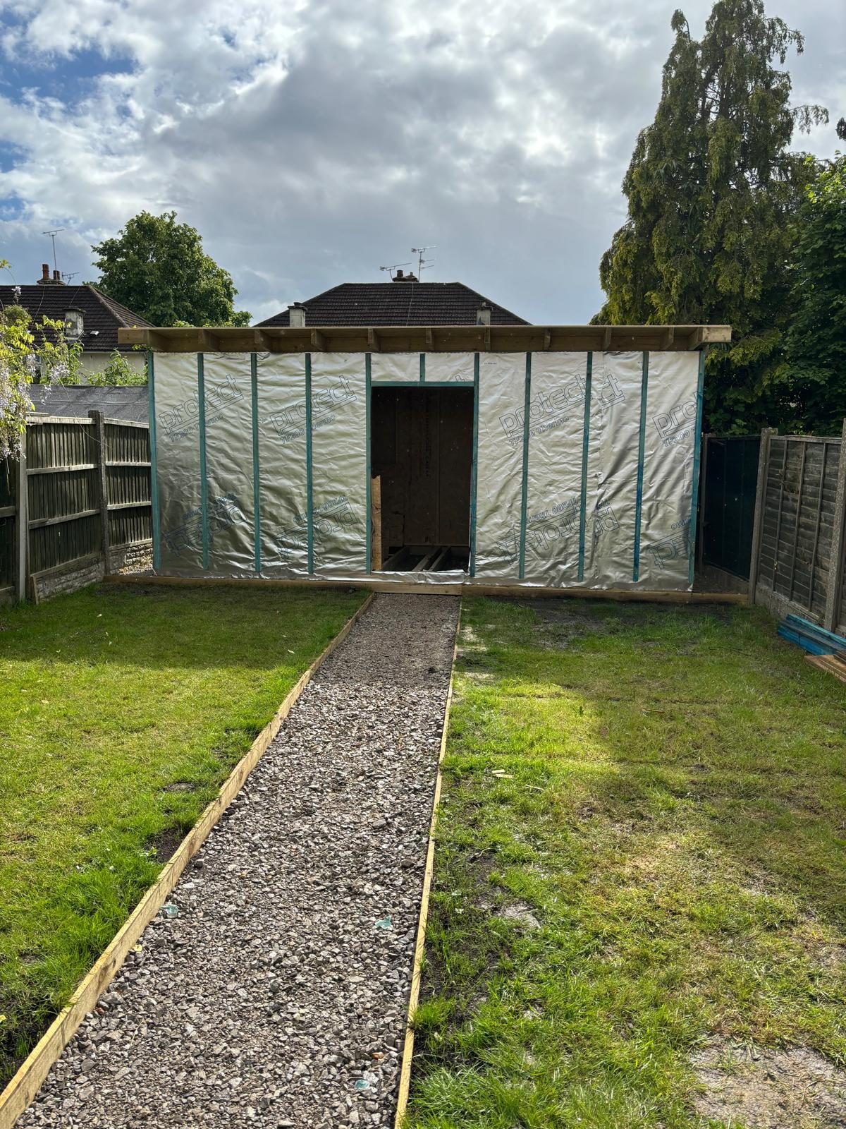 Bespoke grey-clad insulated garden room with a paved path across the lawn