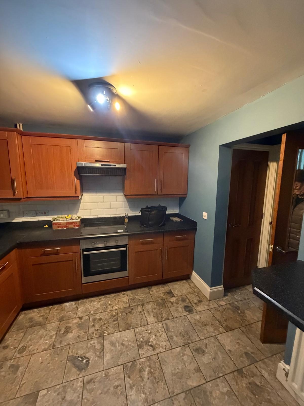 Dated oak kitchen with worn tiled floor before refurbishment